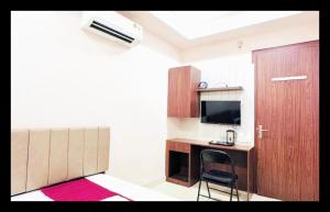 a room with a desk with a chair and a television at The Com Fort Inn 