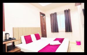 a bedroom with a white bed with red pillows and a window at The Com Fort Inn 