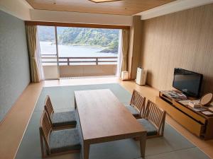 een eetkamer met een tafel en stoelen en een groot raam bij Akazawa Onsen Hotel in Ito
