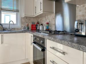 a kitchen with white cabinets and a stove top oven at 19 Salcombe Retreat in Salcombe +5 photos
