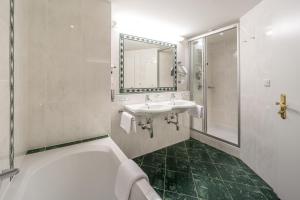 a bathroom with a tub and a sink and a mirror at Hotel Olympia in Obergurgl +125 photos