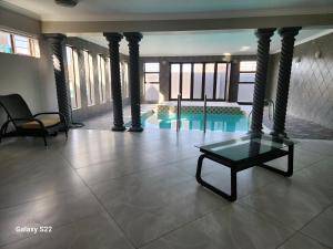 een woonkamer met een tafel en een zwembad bij Pado B & B in Gqeberha