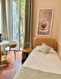 a bedroom with a bed and a table and a window at Nice Garden Hotel in Nice