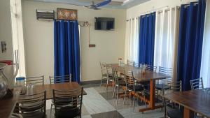 a dining room with tables and chairs and blue drapes at Hotel HBH Himalaya's Beautiful Hills in Uttarkāshi