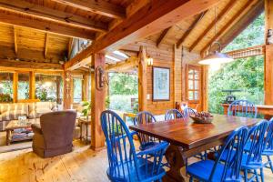 comedor con mesa de madera y sillas azules en BOG Costa de Rio - Piscina climatizada y costa de rio, en Villa La Angostura