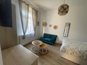 een woonkamer met een blauwe bank en een tafel bij Le Jardin de Phanie, le calme de la campagne en ville in Metz