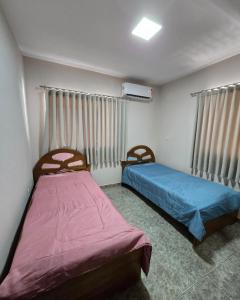ein Schlafzimmer mit zwei Betten und zwei Fenstern in der Unterkunft Residencial Alter do Chao - Apartamento Duplex in Santarém