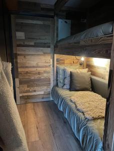 a bed in a room with a wooden wall at Charming studio with terrace and garden in Praz-sur-Arly