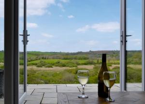 a bottle of wine and two glasses on a table in front of a window at Penally Grange in Tenby