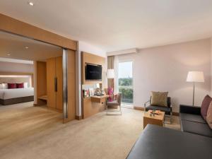 a living room with a couch and a bed at Novotel Yangon Max in Yangon