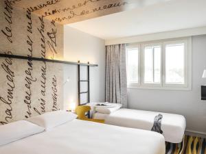 a hotel room with three beds and a window at ibis Styles Meaux Centre in Meaux
