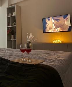 Zwei Gläser Rotwein stehen auf einem Bett. in der Unterkunft The Elysian in Ghaziabad