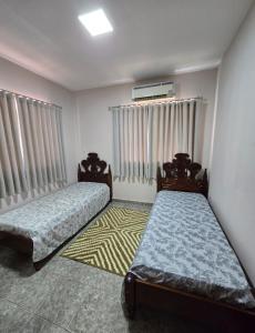 a bedroom with two beds and a window with curtains at Alter do chao - AP na praia! in Santarém +12 photos