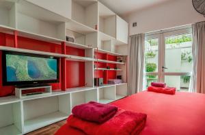 a living room with red and white shelves and a tv at Dos Patios - Luz, tranquilidad y verde in La Plata