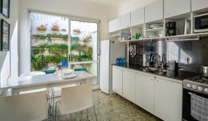 a kitchen with white cabinets and a large window at Dos Patios - Luz, tranquilidad y verde in La Plata
