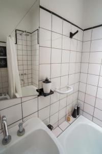 a white tiled bathroom with a sink and a mirror at Dos Patios - Luz, tranquilidad y verde in La Plata +34 photos