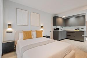 a bedroom with a large white bed and a kitchen at Dobo Madrid Portugal in Madrid +5 photos