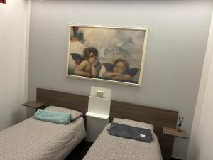 een kamer met twee bedden en een schilderij aan de muur bij Affittacamere Lively in Novara