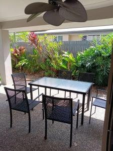 een terrastafel en stoelen met een plafondventilator bij Victoria Point Queen bed & Breakfast in Victoria Point