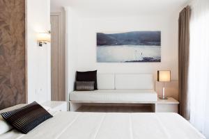 een witte slaapkamer met een wit bed en een bank bij Can Miquel in L'Escala +34 foto's