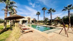 a house with a swimming pool with palm trees at Villa Sbaa Marrakech in Marrakesh