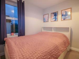 a bedroom with a bed with a orange bedspread and a window at Gordon Avenue in Camberley
