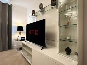 ein Wohnzimmer mit einem Fernseher auf einer Vitrine in der Unterkunft Heathrow Home - 4BR - Sleeps 6 - Free Parking - Work and Family Friendly in Stanwell