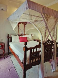 een slaapkamer met een hemelbed bij Stone Town Cafe in Zanzibar City