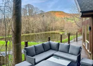 een bank op een veranda met uitzicht op een meer bij Penvale Lakes Lodges in Llangollen