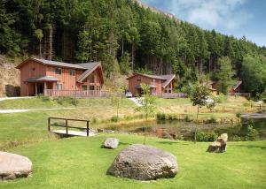 een huis op een heuvel met een vijver en rotsen bij Penvale Lakes Lodges in Llangollen