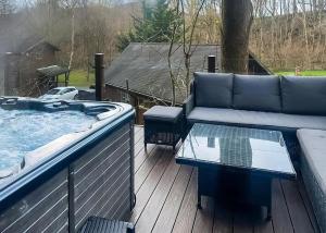 een bank en een tafel op een terras met een jacuzzi. bij Penvale Lakes Lodges in Llangollen