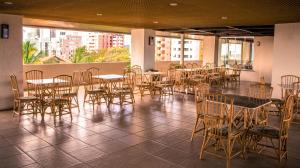 a dining room with tables and chairs and windows at Xênius Hotel in João Pessoa