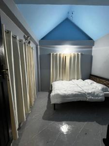 a bedroom with a bed with a blue ceiling and curtains at Amelie Apartments and Stay Inn in Pokhara