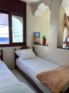 twee bedden in een kamer met twee ramen bij Blue Beach Apartments in Taghazout
