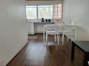 a kitchen with white chairs and a table and a window at Spacious Apartment for 5 in Sodankylä