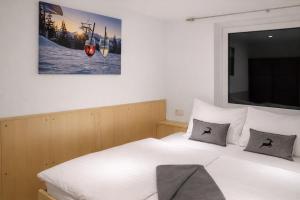 ein Schlafzimmer mit einem weißen Bett mit einem Bild an der Wand in der Unterkunft Haus Dienten Appartements am Hochkoenig in Dienten am Hochkönig
