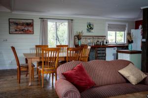 a living room with a couch and a table and chairs at Leura Haven Rustic Mountain Cottage in Leura