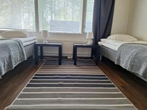 two beds in a room with two tables and a rug at Spacious Apartment for 5 in Sodankylä