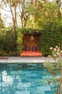 Oasis Garden Marrakech في مراكش: مقعد مع مخدات الجلوس بجانب مسبح +19 صورة