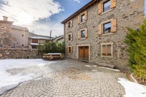 un edificio in pietra con una panchina di fronte di L’Écrin des Angles - Jacuzzi Sauna Hamman privé a Les Angles