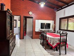 una sala da pranzo con tavolo e sedie e un muro di mattoni di Casa de Campo Pet Friendly com Churrasqueira a Pitangueiras Altre 30 foto