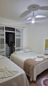 ein Schlafzimmer mit zwei Betten und einem Deckenventilator in der Unterkunft apto 201 in Florianópolis