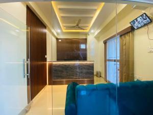 a living room with a blue couch and a tv at Hotel SAFKO Grand - Hopefarm Metro Whitefield in Bangalore