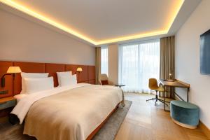 巴塞尔Mövenpick Hotel Basel的一间酒店房间，配有一张大床和一张书桌