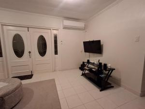 a living room with two white doors and a tv at Pams Lodge Barbados in Christ Church