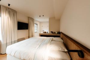 a bedroom with a large white bed and a television at Alfred Hotel & Gastro Bar in Marche-en-Famenne