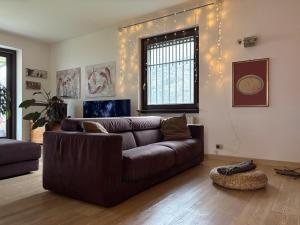 a living room with a brown couch and lights on the wall at Parirolo B&B in Tresivio