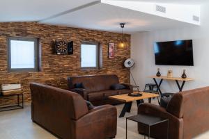 Il comprend un salon doté d'un mobilier en cuir et d'un mur en briques. dans l'établissement Bastide des Oliviers, Maison Provençale, à Boulbon