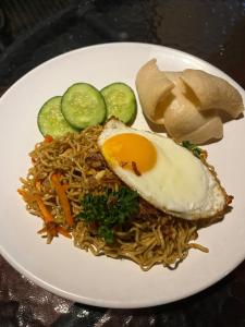 a plate of noodles with an egg and pickles at Batan Bingin House in Ubud
