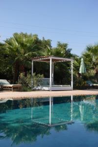 a swimming pool with a gazebo and palm trees at Riad SABIDI in Essaouira